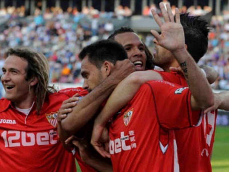 Jugadores celebrando un gol con el Sevilla FC en un partido de fútbol.