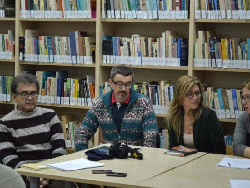 Reunión en biblioteca con libros en estanterías al fondo.