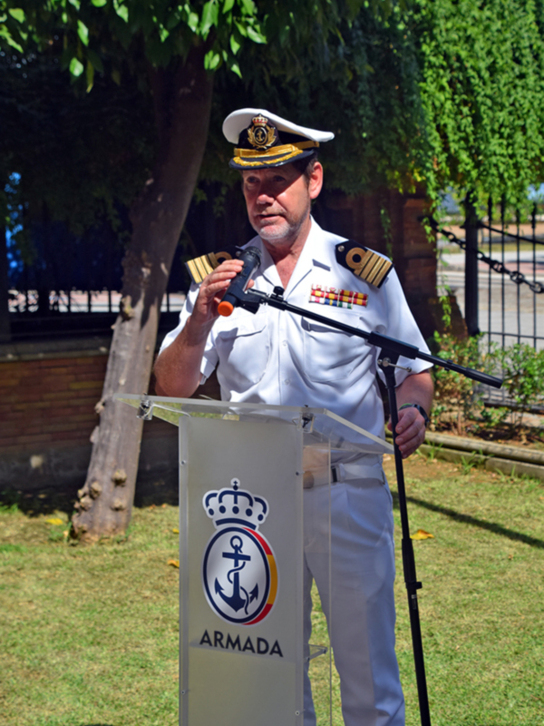 Un hombre de uniforme militar de la Armada de España, con un sombrero de almirante y un microfono, habla en un podio con el logotipo de la Armada de España.